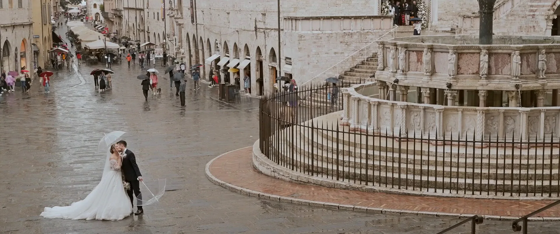 Arturo and Susanna under an umbrella by the Fontana Maggiore in Piazza IV Novembre, Perugia, a frame from their wedding film