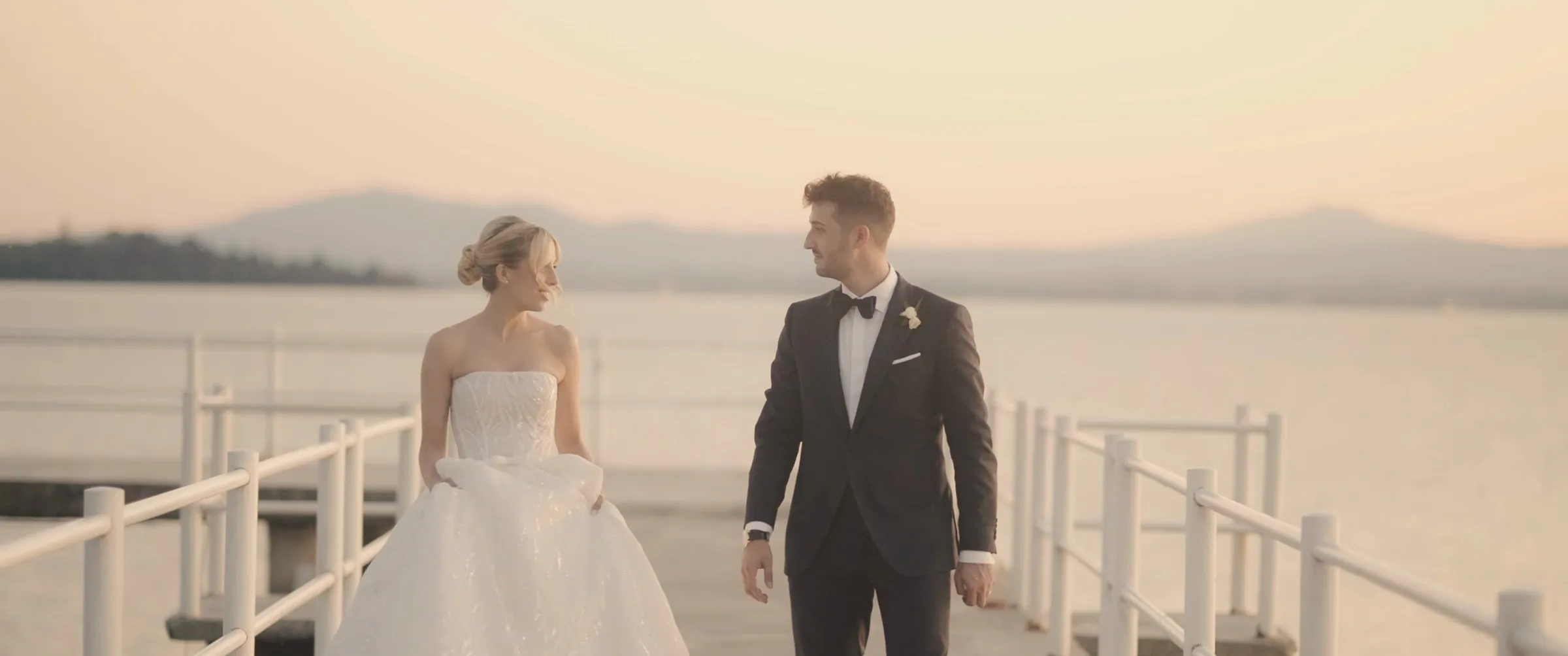 Emanuele and Elena on a pier on Lake Trasimeno at sunset, a frame from their wedding film