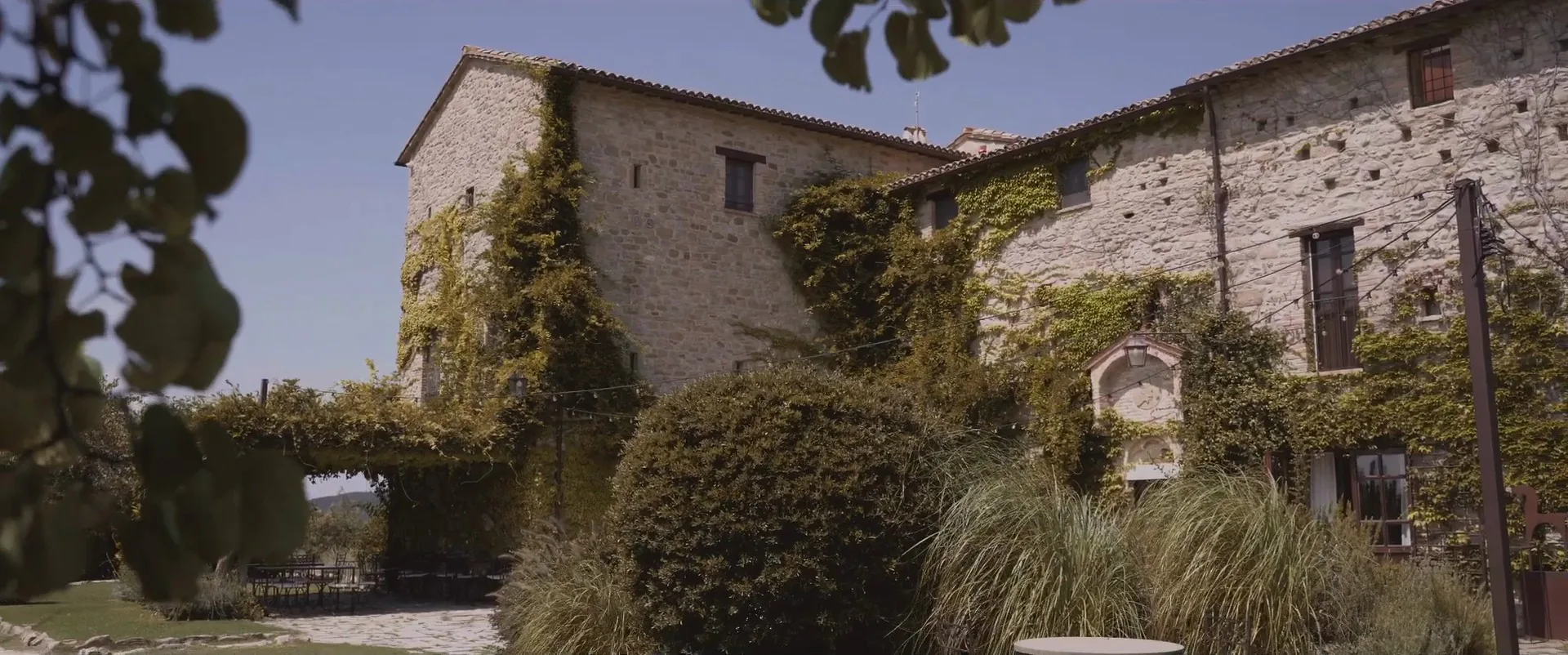 The ivy-covered stone façade of Castello di Petrata, Assisi, a frame from Luigi and Christina’s wedding film