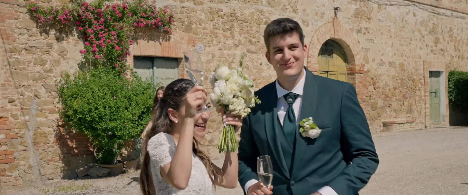 Matilde raising her bouquet in the courtyard beside Federico, a frame from their wedding film