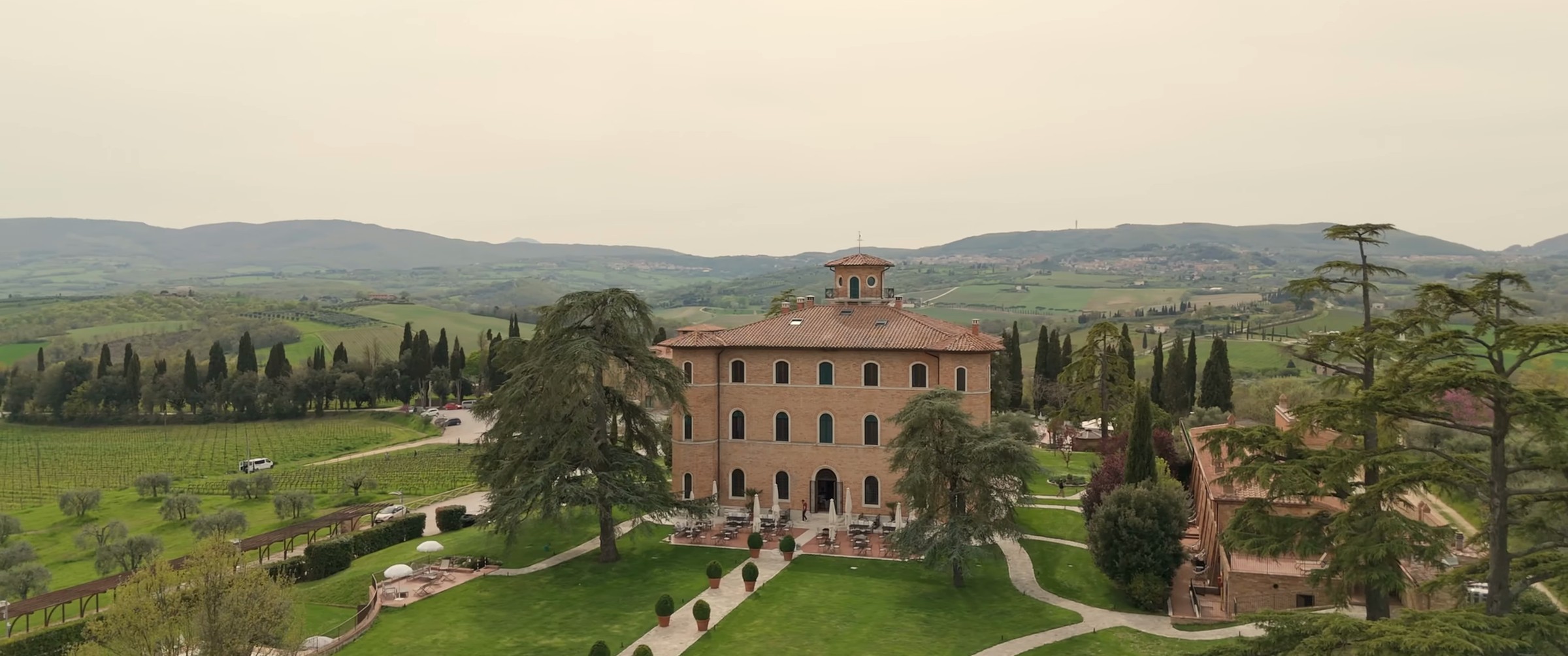 La villa in mattoni di Poggio alla Sala tra giardini, cipressi e vigneti, ripresa dal drone, fotogramma dal film di Lin e Wei
