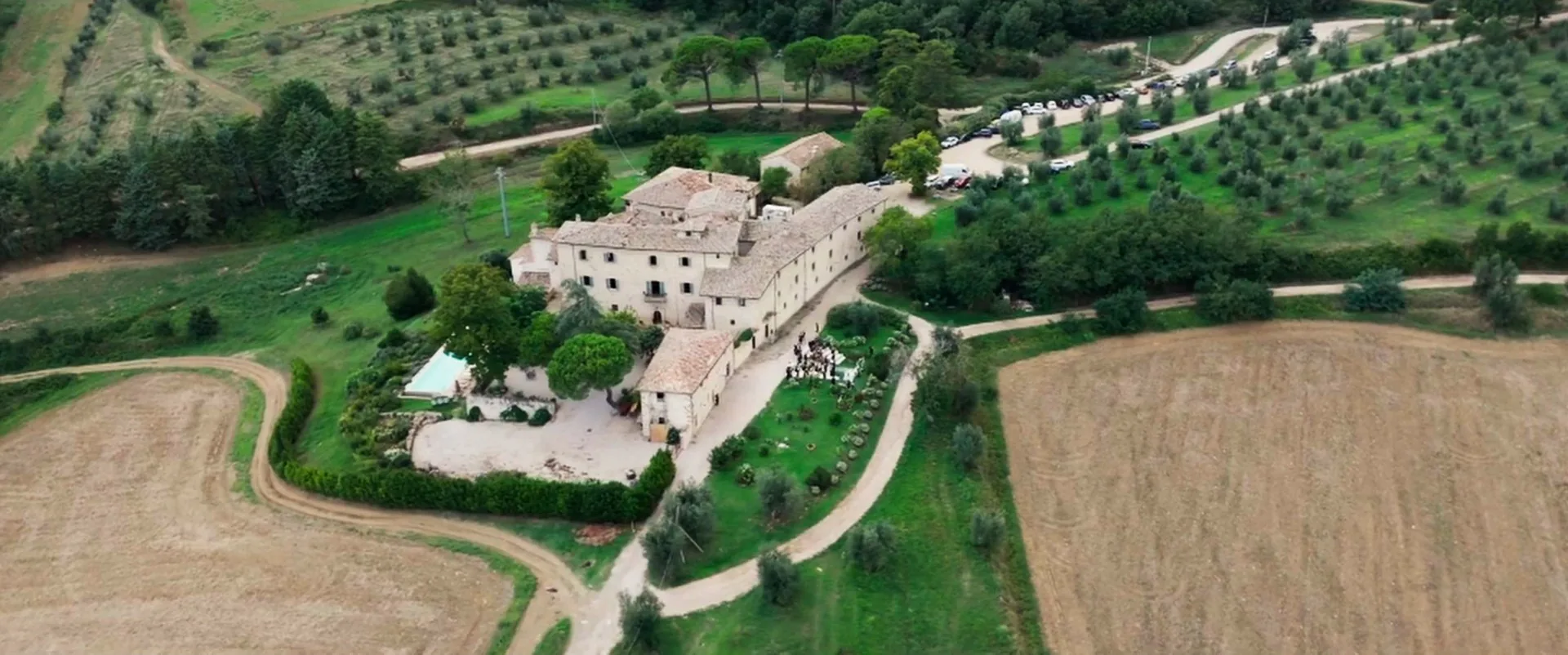 Borgo Colognola among olive groves and fields, seen by drone, a frame from Valerio and Maral’s wedding film