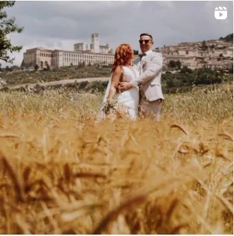 Couple embracing in a wheat field in front of Assisi — Cinemarry Instagram reel